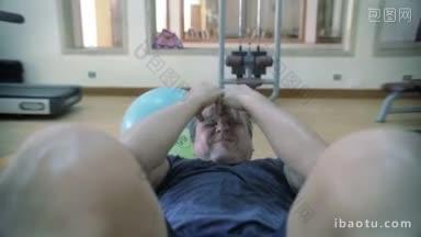 在健身中心定期训练的慢动作成熟男子在腹部长凳上做仰卧起坐，感到疲劳和出<strong>汗</strong>